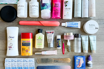 A flat lay of various beauty and skincare products, including shampoos, lotions, lip balm, and tools on a wooden surface.